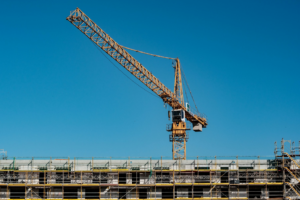 A large crane working over a large metal building.