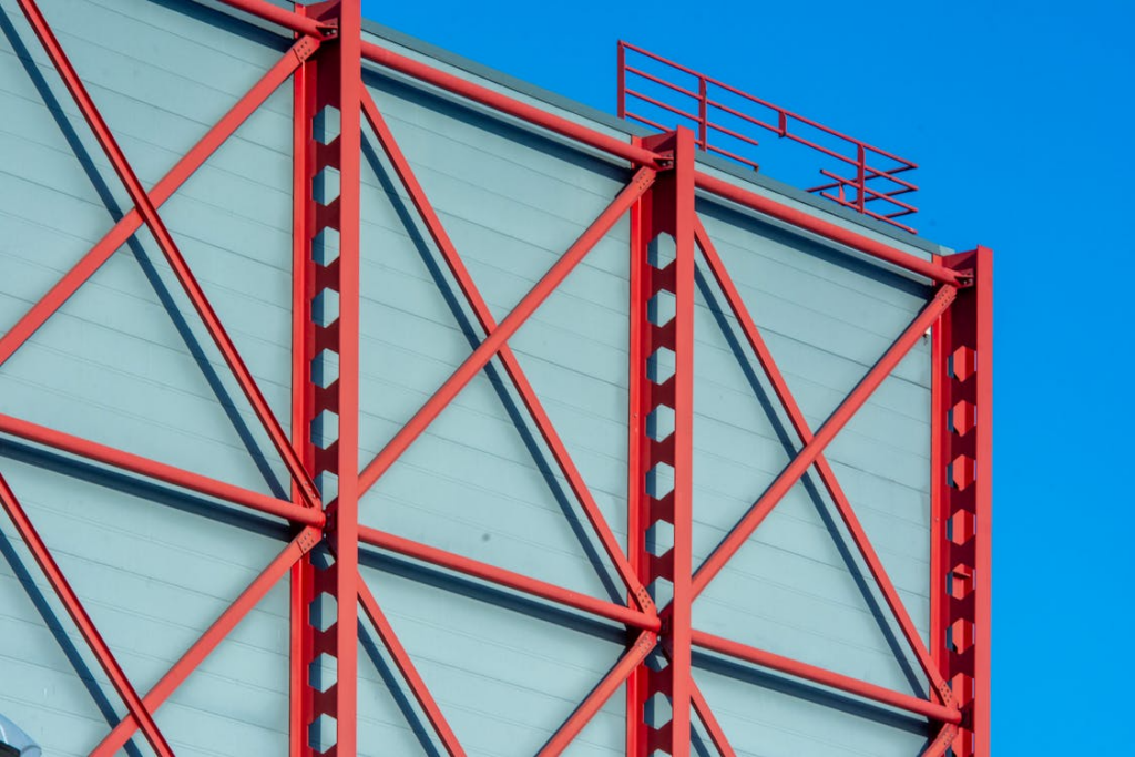 Red steel frame structure used in modern barndominium construction against blue sky