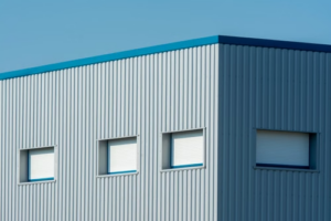 A sleek industrial building with a corrugated metal facade featuring roller blinds and sandwich panels