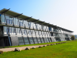 A large steel building with a field nearby.